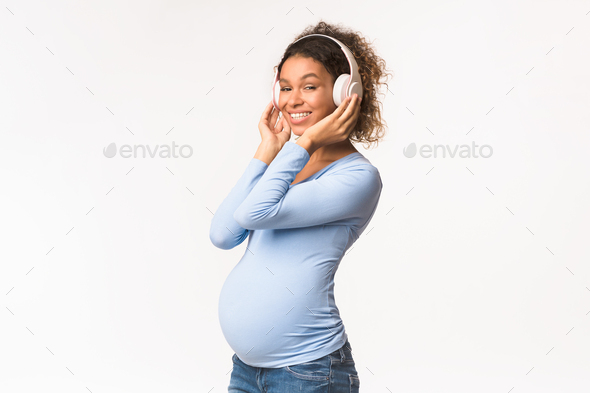 Pregnancy and motherhood concept. Black pregnant woman listening music