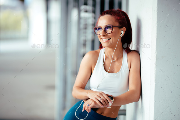 Woman listening to music, doing workout exercises on concrete background - Stock Photo - Images