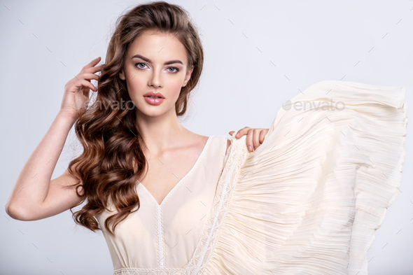 Portrait of a beautiful woman with a long hair in a beige dress.