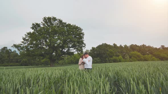 A Young Couple with Their Newborn Baby in Green Wheat in a Field alt