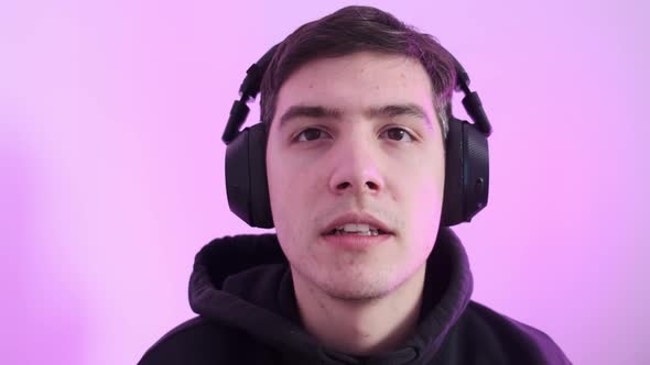 A Young Man Puts on His Wireless Headphones and Plays Computer Games alt