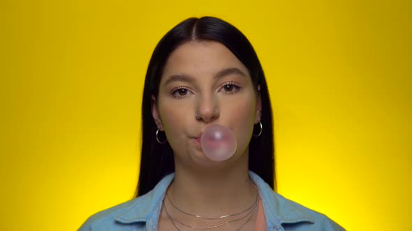 Attractive Smiling Woman Looking at Camera and Blowing Bubble Gum