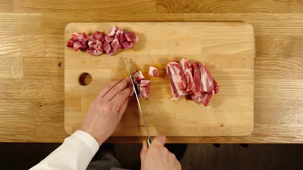 Cook Takes Knife And Cuts Pork Into Slices And Then Into Pieces