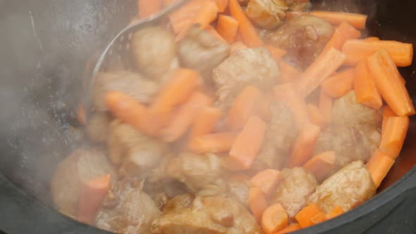 Cooking Process, Frying Pork Meat With Carrots and Onion in Large Cauldron on Open Fire. 