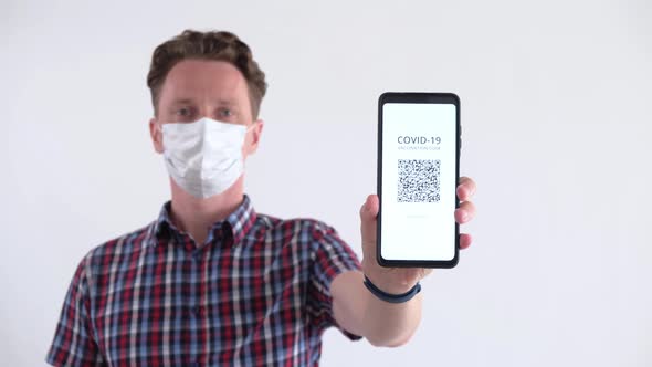 Men in Face Mask Showing QR Code of Vaccination on a Smartphone