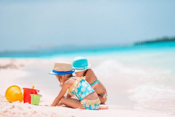 Two little happy girls have a lot of fun at tropical beach playing together  Stock Photo by travnikovstudio