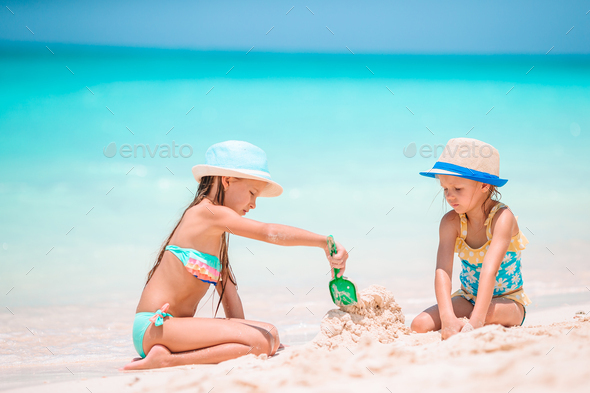 Two little happy girls have a lot of fun at tropical beach playing