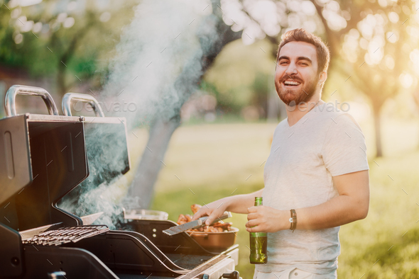 Portrait of laughing handsome guy having a great time at barbecue grill party