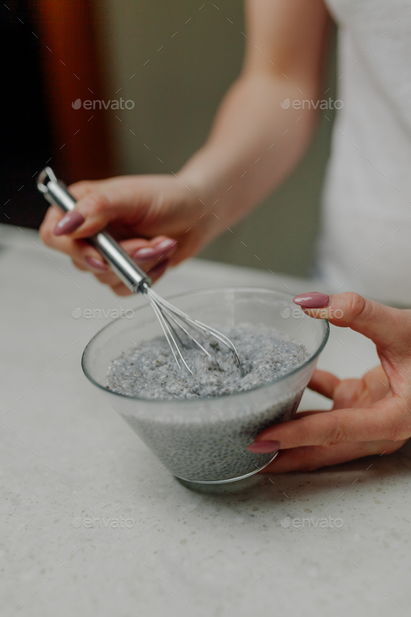 Woman Mixing Chia Pudding in Glass Bowl in Kitchen - Stock Photo - Images