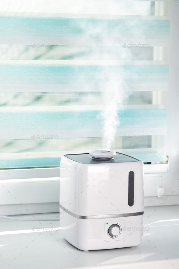 The white ultrasonic humidifier on a window moistens dry air