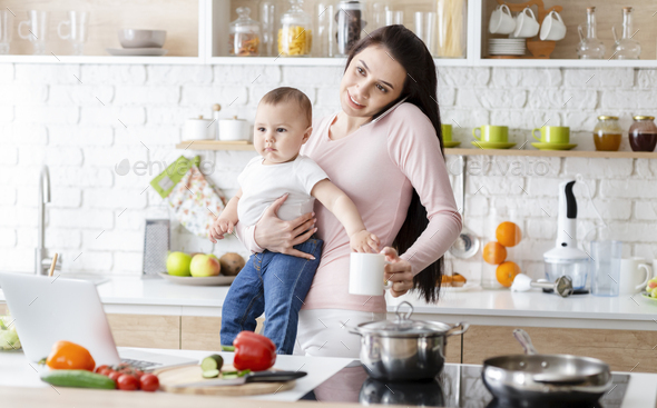 Young Mom Talking On Phone And Holding Baby At Kitchen Stock Photo By Prostock Studio