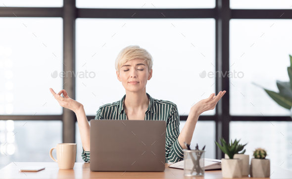 Mature Businesswoman Meditating Relaxing Sitting In Modern Office