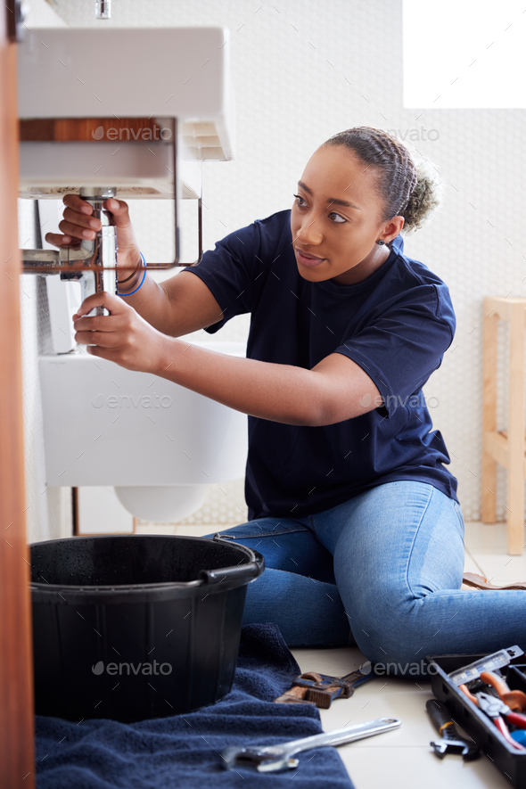 Female Plumber Working To Fix Leaking Sink In Home Bathroom - Stock Photo - Images