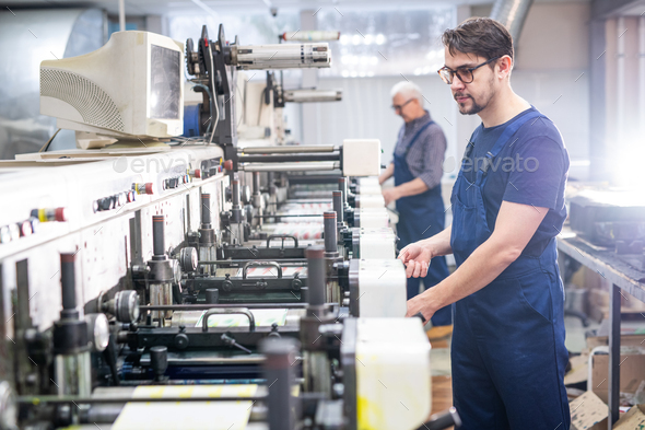 Young employee of printing plant at work