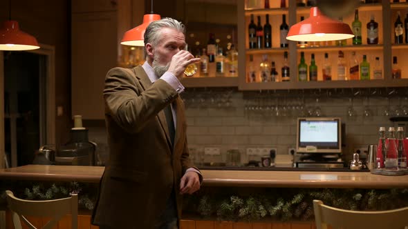 Lonely solid gray-haired adult man drinking whiskey alone at the bar alt