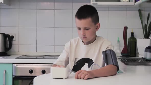 Man measures his own pulse at home sitting at the table. Automatic heart rate monitor