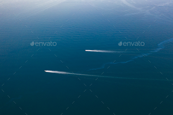 Drone view of sailing boats in deep blue clear water.