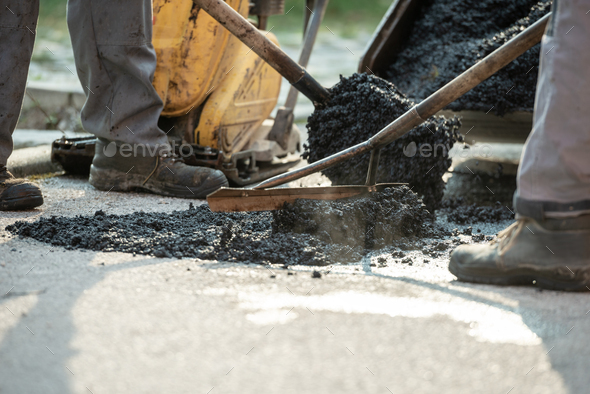 Two construction workers patching bump in the road - Stock Photo - Images