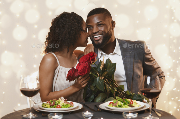 Romantic guy giving bunch of roses to his pretty girlfriend