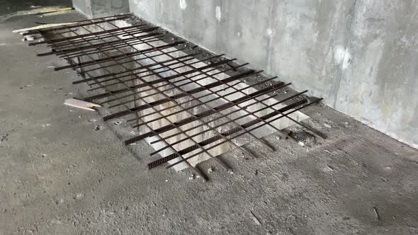 A Large Rectangular Hole in the Concrete Floor is Blocked By an Iron Grating at a Construction Site alt