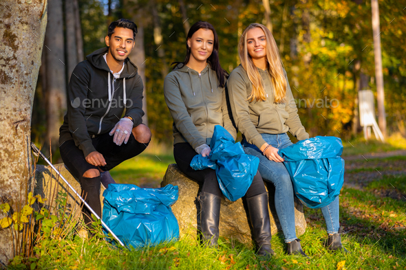 Female volunteers picking up garbage on grass - Stock Photo - Images