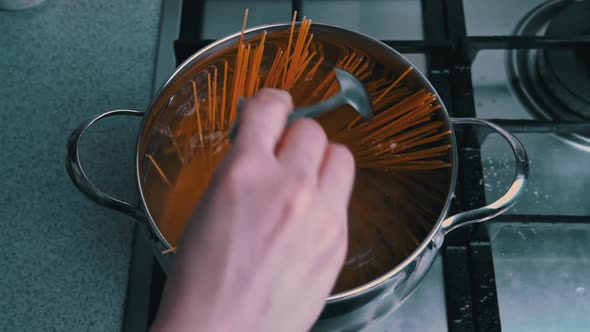 Female Hands Stir Spaghetti in a Saucepan with Boiling Water Slow Mo alt