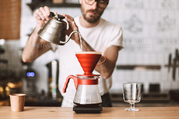 Close up photo of barista standing at counter and preparing pour over coffee in cafe