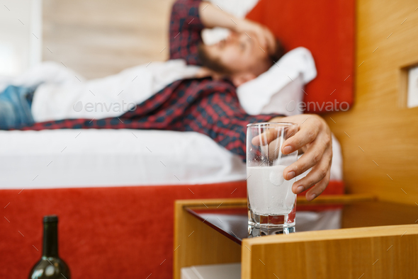 Hangover man holding a glass with soluble tablet