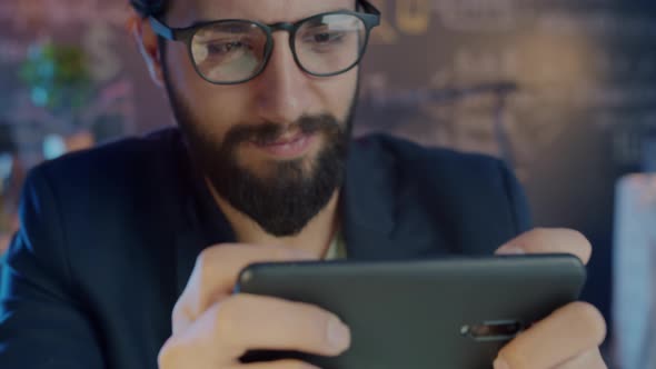Closeup of Happy Middle Eastern Employee Playing Video Game Using Smartphone at Work at Night alt