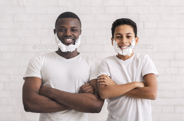 Black father and sun posing with foam beard and folded arms