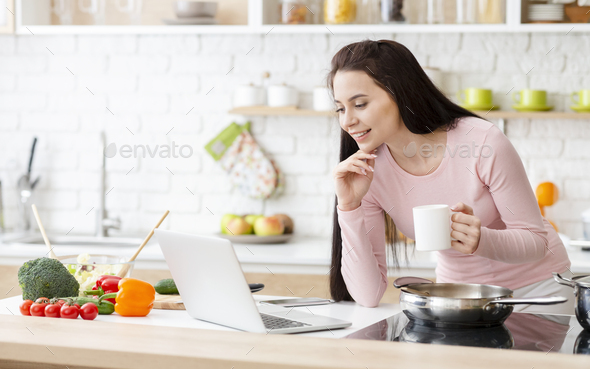 Young business lady searching on laptop and enjoying coffee