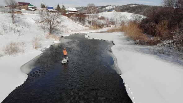 a Man with a Hat Paddling on a Paddle Board in Winter alt