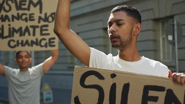 Two mixed race men on a protest march holding placards raising hands and shouting alt