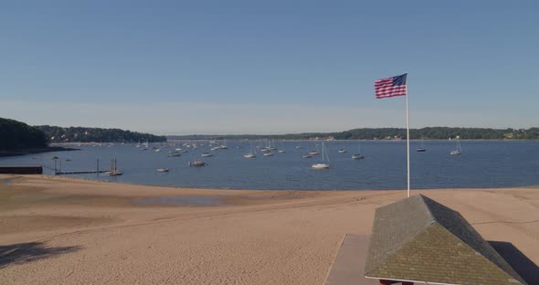 Flying Over a Sandy Beach Shore and Towards Boats Anchored in the Water alt