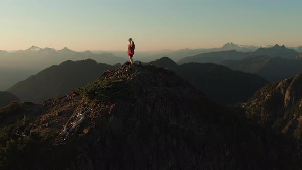 Adventurous Caucasian Woman Hiking on Top of a Rocky Mountain Cliff alt
