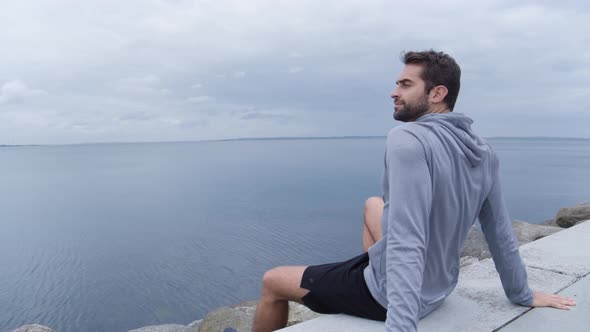 Serious Athlete Sitting Looking Out To Sea