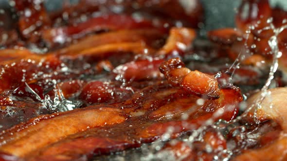 Super Slow Motion Shot of Roasted Bacon Slices Falling Into Pan at 1000 Fps. alt