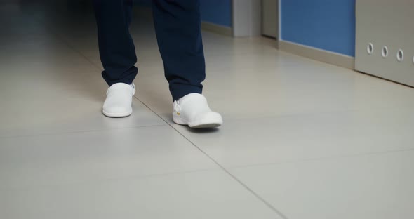 A Man in White Rubber Shoes Walks Along the Corridor of the Hospital alt