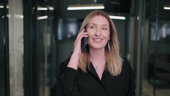 Smiling Businesswoman Looking on Cellphone Indoors alt