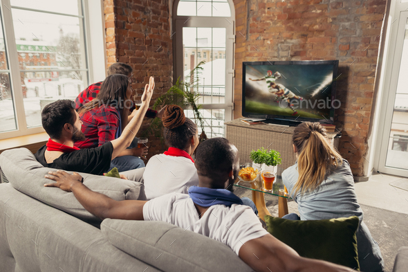 Excited group of people watching sport match at home