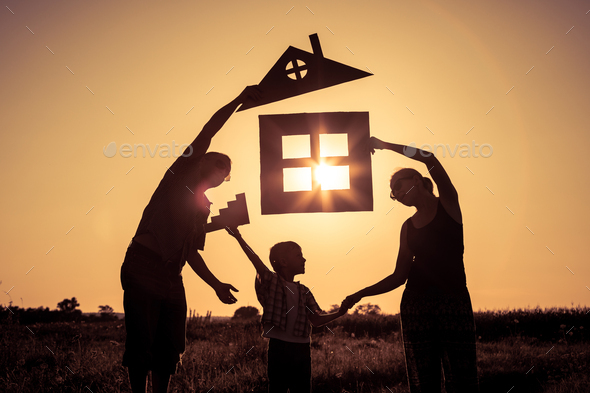 Happy family standing on the field at the sunset time. They build a house. - Stock Photo - Images