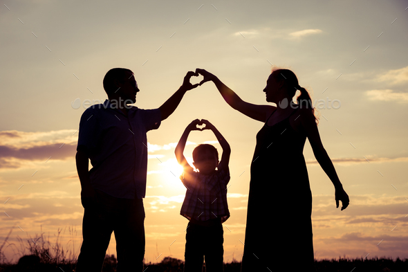 Happy family standing in the park at the sunset time. - Stock Photo - Images