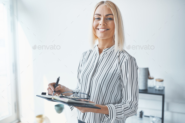 Smiling young businesswoman writing notes while working in an office
