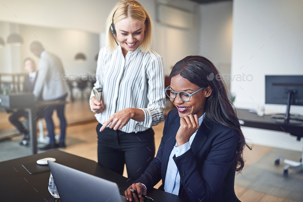 Laughing businesswomen looking at something on a laptop at work