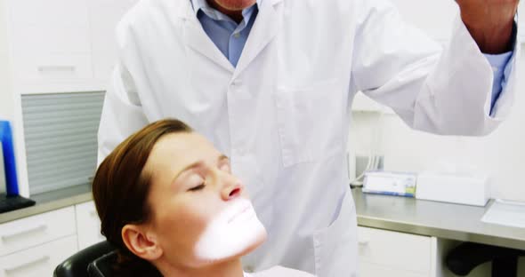 Dentist adjusting dental light over female patient alt