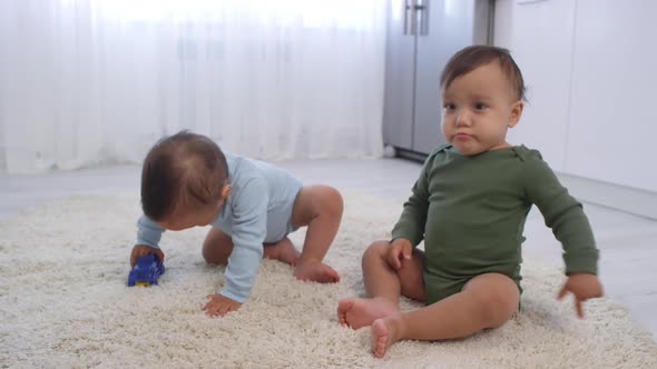 Asian Twin Baby Boys Playing on Carpet with Toy Car alt