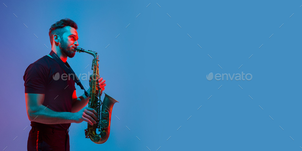 Young caucasian jazz musician playing the saxophone in neon light, flyer