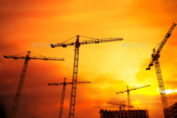 Industrial background with cranes over sunset sky - Stock Photo - Images