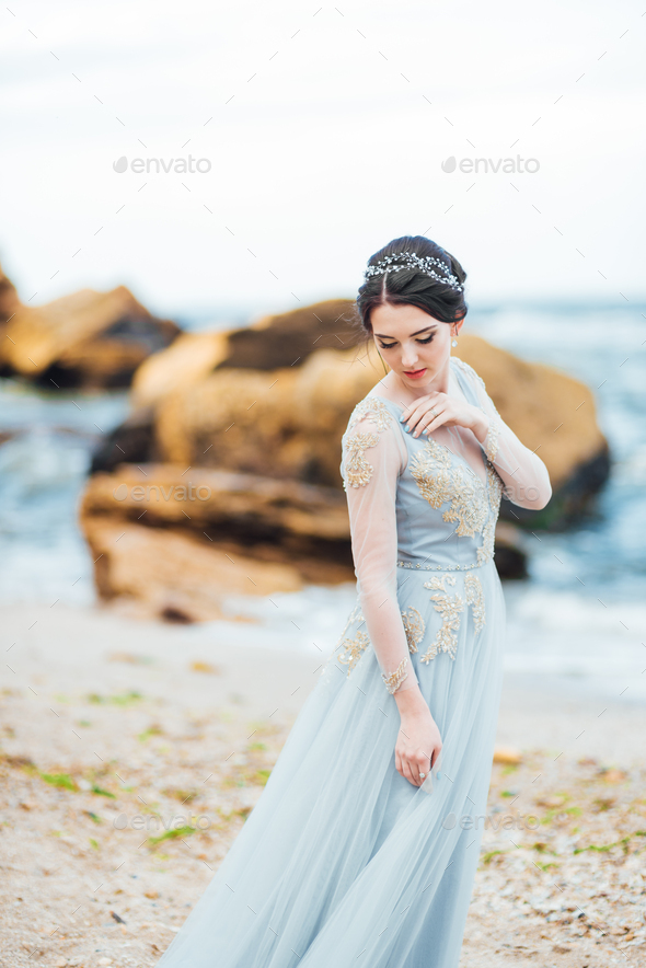 bride in a blue light dress walking along the ocean Stock Photo by ...