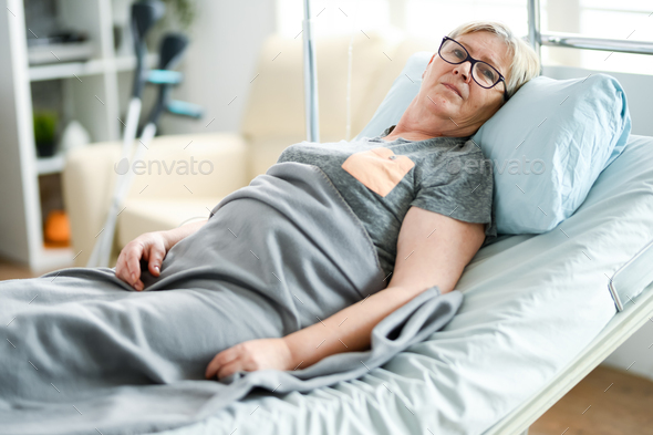 Elderly age woman laying on a bed in a nursing home